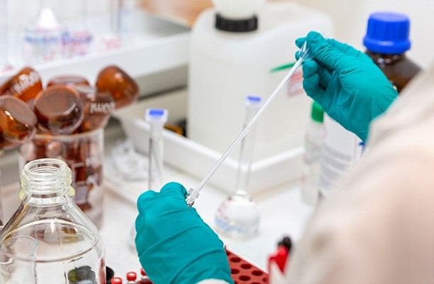 Scientist wearing green gloves and test tube Min